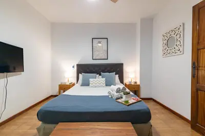 a bedroom with a large bed with a blue blanket at Travel Habitat Casa con embarcadero. in Port Saplaya