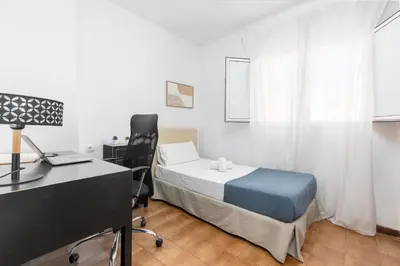 a bedroom with a bed and a desk with a computer at Travel Habitat Casa con embarcadero. in Port Saplaya