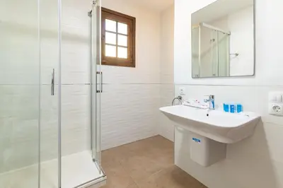 a white bathroom with a sink and a shower at Travel Habitat Casa con embarcadero. in Port Saplaya