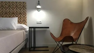 a bedroom with a bed and a chair next to a table at MD Design Hotel - Portal del Real in Valencia