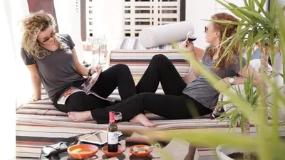 two women sitting on a bed looking at their cell phones at MD Design Hotel - Portal del Real in Valencia