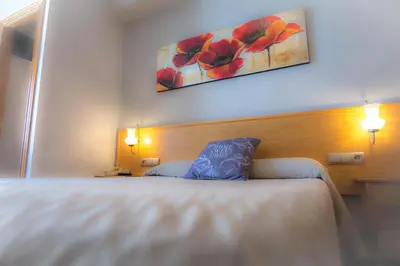 a bedroom with a bed and a painting on the wall at L'Oncle Pere Habitacions in L'Alcúdia