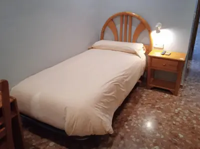 a bedroom with a white bed and a nightstand with a bed sidx sidx sidx at L'Oncle Pere Habitacions in L'Alcúdia