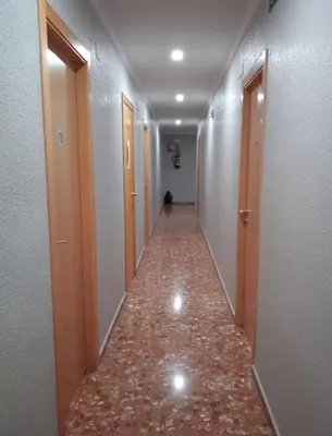 a hallway with a long corridor with wooden doors at L'Oncle Pere Habitacions in L'Alcúdia