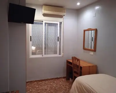 a bedroom with a bed and a desk and a window at L'Oncle Pere Habitacions in L'Alcúdia