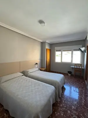 two beds in a hotel room with two windows at L'Oncle Pere Habitacions in L'Alcúdia
