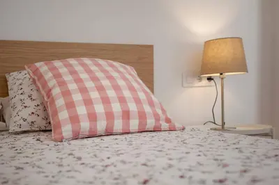 a bed with a pink and white pillow and a lamp at Habana Apartment in Valencia