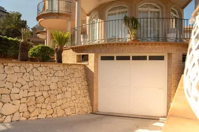 a white garage door in front of a house at MD Villa Cullera Cap Blanc in Faro de Cullera