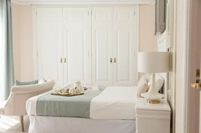 a white bedroom with a bed and a chair at MD Villa Cullera Cap Blanc in Faro de Cullera