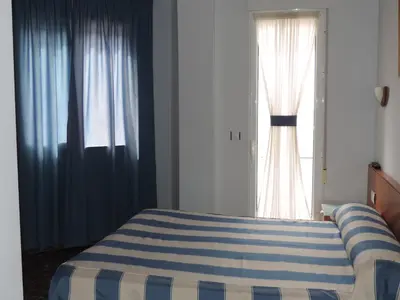 a bedroom with a blue and white bed and a window at Hotel Costa San Antonio in Cullera