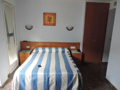 a bedroom with a bed with a blue and white striped blanket at Hotel Costa San Antonio in Cullera