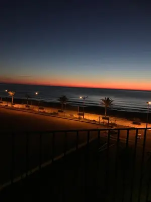 a beach with palm trees and the ocean at sunset at Apartamento PortSaplaya in Port Saplaya