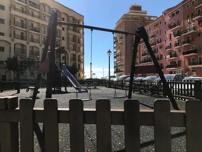 a playground with swings in a city at Apartamento PortSaplaya in Port Saplaya