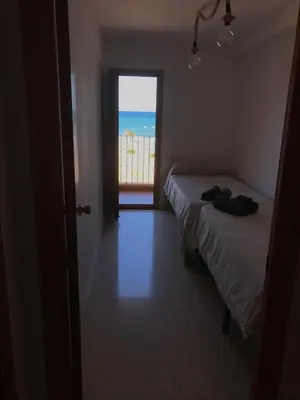 a bedroom with two beds and a window with the ocean at Apartamento PortSaplaya in Port Saplaya