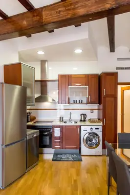 a kitchen with stainless steel appliances and wooden cabinets at Travel Habitat Jardines Rio Turia. in Valencia