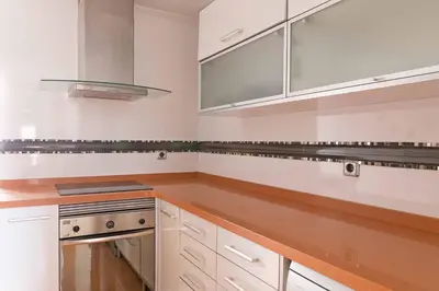 a kitchen with white cabinets and a wooden counter top at Attic Valencia Beach in Valencia