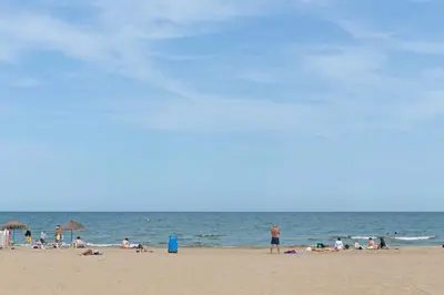 a group of people on a beach with the ocean at Attic Valencia Beach in Valencia
