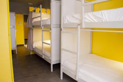 a room with three bunk beds with yellow walls at room00 Valencia Hostel in Valencia