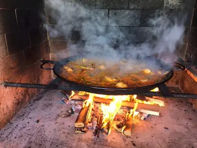 a large pan of food cooking on a grill at La perla de oasis in Lliria