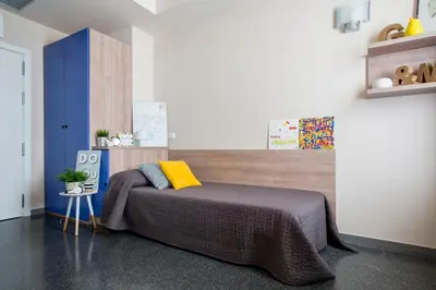 a bedroom with a bed with a yellow pillow on it at Residencia Universitaria Resa Damia Bonet in Valencia