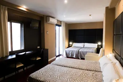 a hotel room with two beds and a desk at Hotel Benetusser in Benetúser