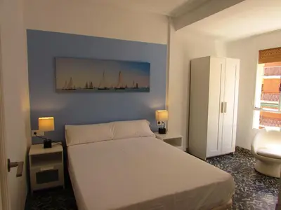 a bedroom with a white bed and a blue wall at Cullera Beach by Zagal Apartments in Cullera