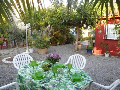 a table with a green table cloth and white chairs at Casa con jardín frente Playa de Burriana in Burriana