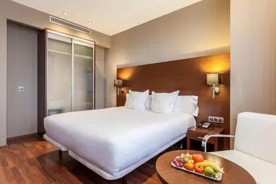 a hotel room with a bed and a bowl of fruit on a table at AZZ Valencia Congress Hotel & Spa in Paterna