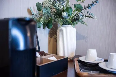 a table with a white vase with flowers and a box at AZZ Valencia Congress Hotel & Spa in Paterna