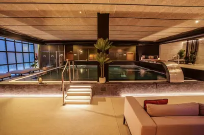 a swimming pool in a building with a couch at AZZ Valencia Congress Hotel & Spa in Paterna