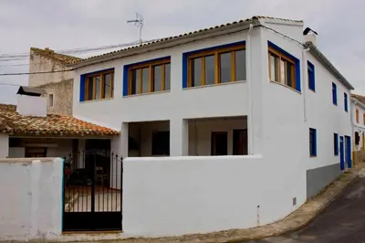 a white house with blue windows on a street at El mirador del norte in Cortez de Pallas