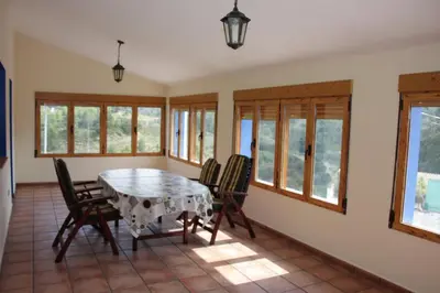a dining room with a table and chairs and windows at El mirador del norte in Cortez de Pallas