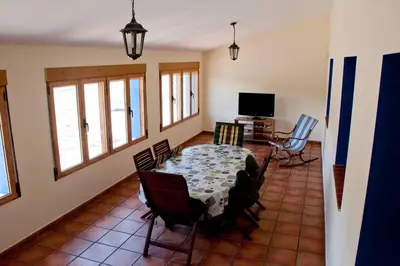 a dining room with a table and chairs and a television at El mirador del norte in Cortez de Pallas