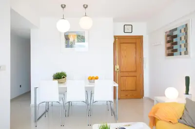 a white dining room with a table and chairs at Apartments Cullera Beach in Cullera