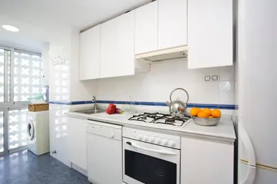 a kitchen with white cabinets and a stove top oven at Apartments Cullera Beach in Cullera