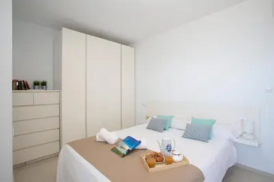 a white bedroom with a bed with white cabinets at Apartments Cullera Beach in Cullera