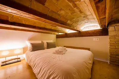 a bedroom with a large white bed with a wooden ceiling at MD Sueca in Valencia