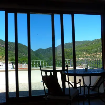 a table and chairs in front of a window with mountains at Dalt Vila in Eslida