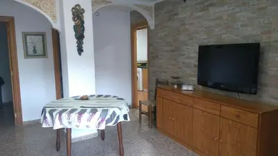 a living room with a tv on a dresser and a table at Apartamento a 10 metros del mar in Cullera