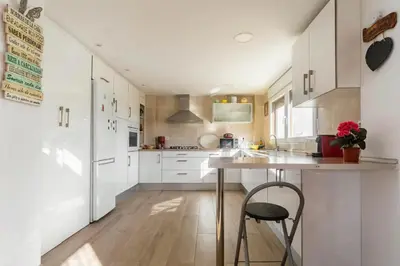 a kitchen with white cabinets and a wooden floor at Ca Emma in Mahuella