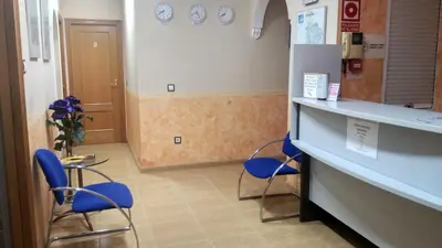 a waiting room with blue chairs and a counter at Hotel Beatriz in Burriana