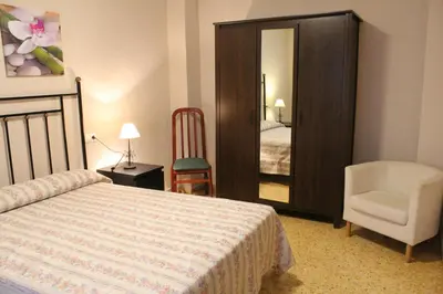 a bedroom with a bed and a chair and a mirror at Piso Colon in Paiporta