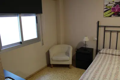 a bedroom with a chair and a bed and a window at Piso Colon in Paiporta