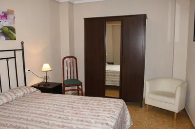 a bedroom with a bed and a chair and a mirror at Piso Colon in Paiporta