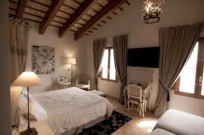 a bedroom with a bed and a chair and windows at La Mozaira in Alboraya