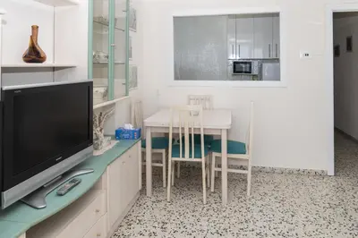 a living room with a table and a tv and a kitchen at Apolo, 3º-16 in Cullera