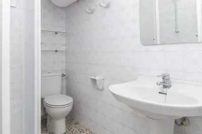 a white bathroom with a toilet and a sink at Apolo, 3º-16 in Cullera