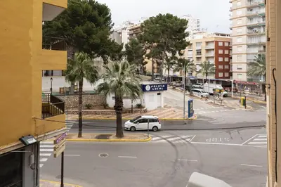a white car driving down a street with palm trees at Estirpe, 2º-4 in Cullera