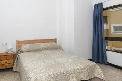 a bedroom with a bed and a blue curtain at Estirpe, 4º-8 in Cullera