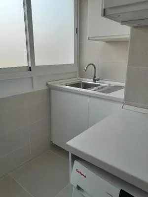 a white kitchen with a sink and a counter at Estrella, 6º-36 in Cullera